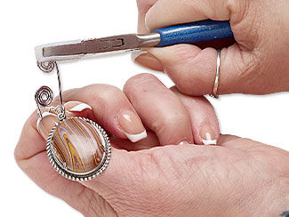 hand using flat nylon-jaw pliers gripping spiral on cabochon setting